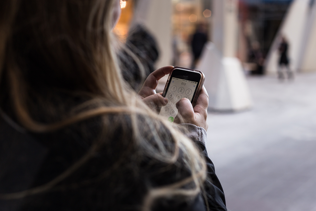 Woman with long hair dialing on her iPhone.